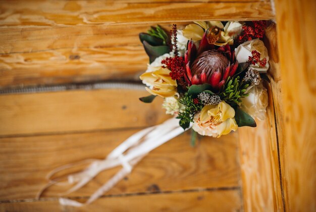 Свадебный букет из осенних цветов стоит на скамейке