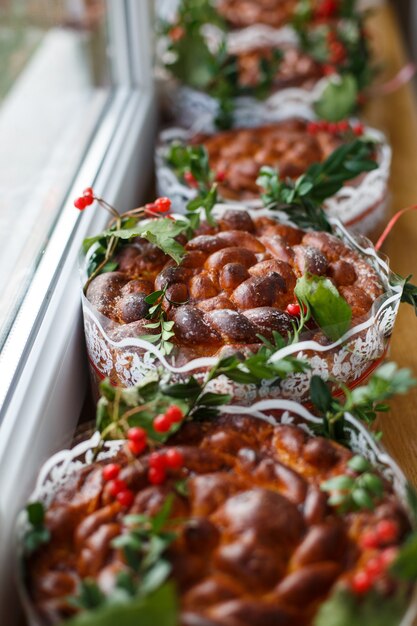 Wedding breads decorated with green leaves and berries stand on