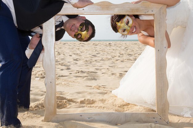 Wedding coupke with mask on the beach