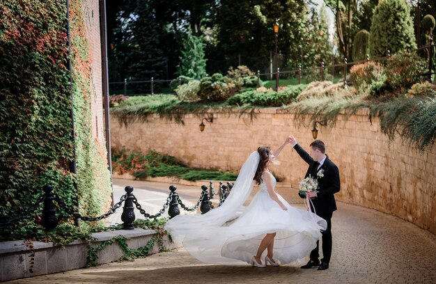 Wedding couple is dancing near stone wall covered with green ivy