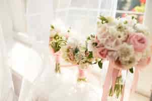 無料写真 結婚式の装飾花嫁とブライドメイドの明るいピンクのバラの花束は窓の前に立つ