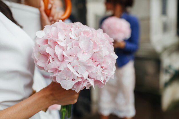 웨딩 정보. 신부는 그녀의 팔에 부드러운 핑크 꽃다발을 보유하고있다. 얼굴 없음