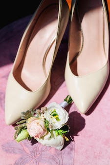 Wedding details, bride's shoes, boutonniere. beige leather shoes with heels