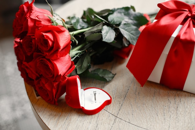 Wedding ring on the girl's finger. Bouquet of red roses. Engagement gift.