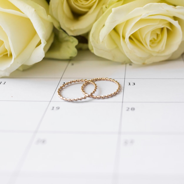 wedding rings on calendar date with yellow roses