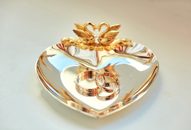 Wedding rings lie on the beautiful golden plate decorated