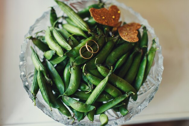 Wedding rings lie on green French beans 