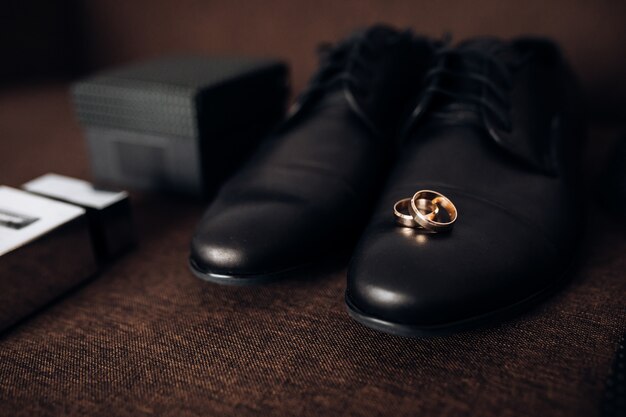 Обручальные кольца лежат на мужской обуви