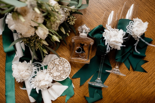 Wedding rings lie on the perfume bottle near flowers