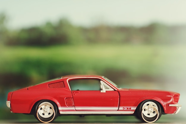 Wedding rings lie behind the wheels of a toy red Mustang 