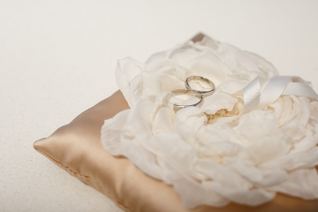 Wedding rings made of white gold lie on the cloth flower