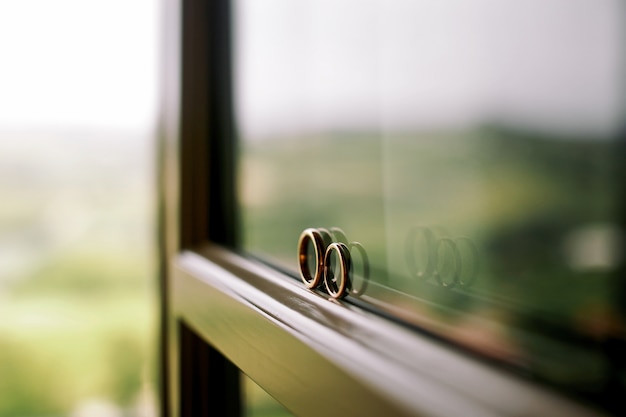 Free photo wedding rings stand on the window