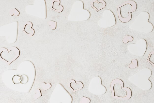 Wedding rings on white heart shape over the concrete backdrop