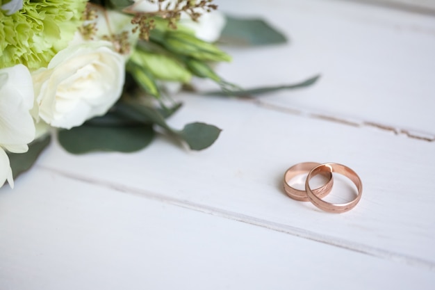 wedding rings with white roses on wooden table