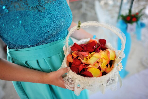 バスケットの花嫁介添人の手で結婚式のバラの花びら