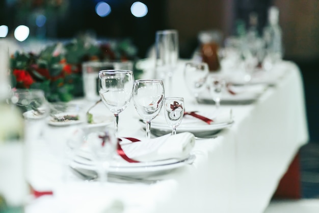 Свадебный стол с белыми салфетками и красными лентами