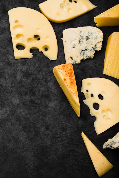 Wedges and slices of cheese on black kitchen worktop