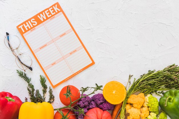 Weekly meal plan with colorful fruits and vegetables on textured background