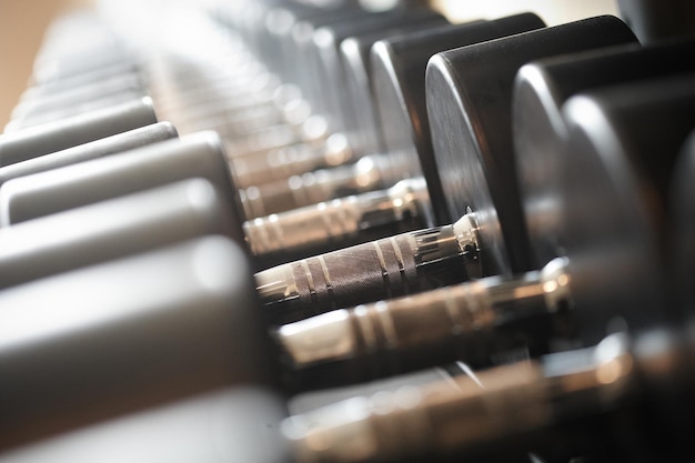 Weight training equipment in a modern gym indoors. Close-up image of dumbells on a stand. Gym equipment.