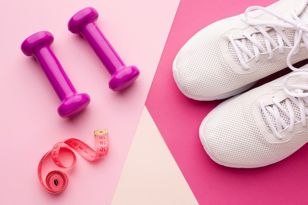 Weights sneakers and meter on pink background