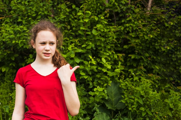 Weird girl pointing to the side with thumb up in park