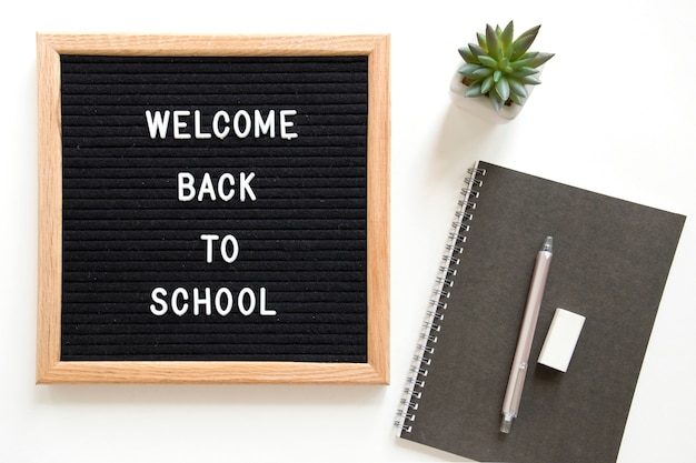 Welcome back to school text on slate near stationeries over white background