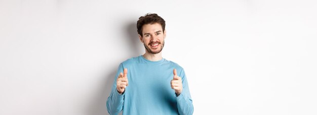 Foto gratuita ben fatto, bell'uomo sorridente, che punta il dito verso la telecamera per congratularsi o elogiare il buon lavoro