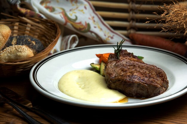 Well-done steak with mashed potatoes and fried vegetables