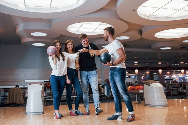 Well done. Young cheerful friends have fun in bowling club at their weekends