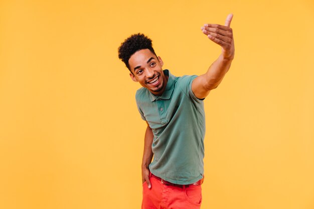 Well-dressed black man with short hair posing emotionally. Portrait of joyful guy in green t-shirt.