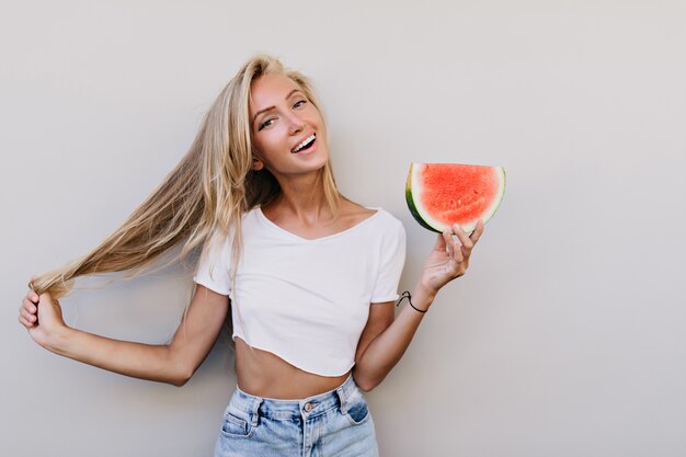 Well-dressed happy woman holding slice of watermelon.