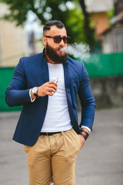 Free photo well-dressed man smoking electronic cigarette