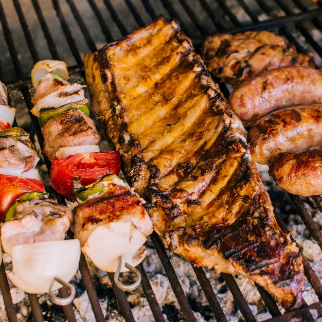 Well grilled meat pieces and vegetables on grill charcoal