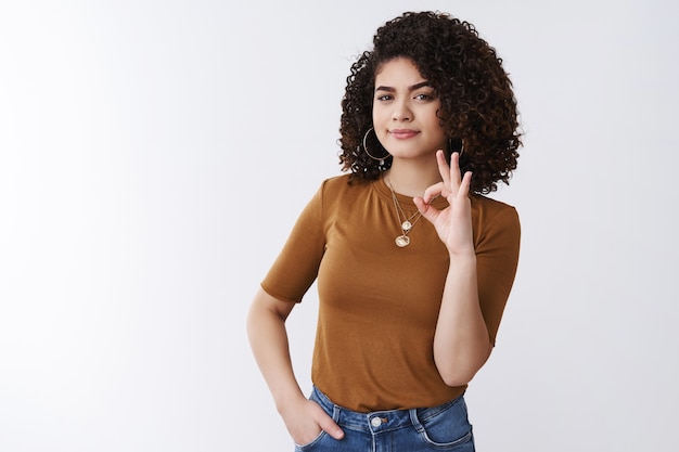 Well okay. Serious-looking confident young female entrepreneur agrees terms look doubtful take decision give approval show ok fine good gesture encourage friend see efforts, white background