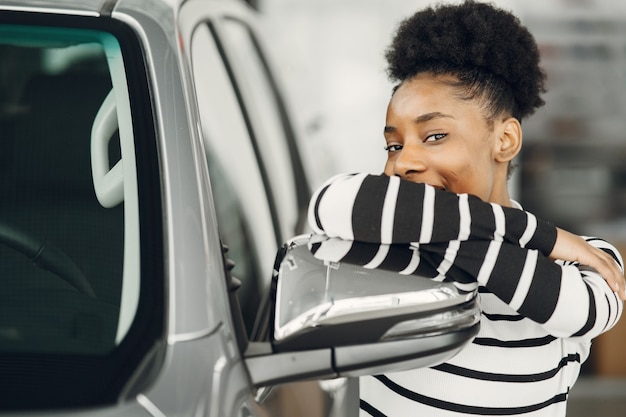 Foto gratuita oggi sono andato a fare shopping. inquadratura di una donna africana attraente spara a un'auto.