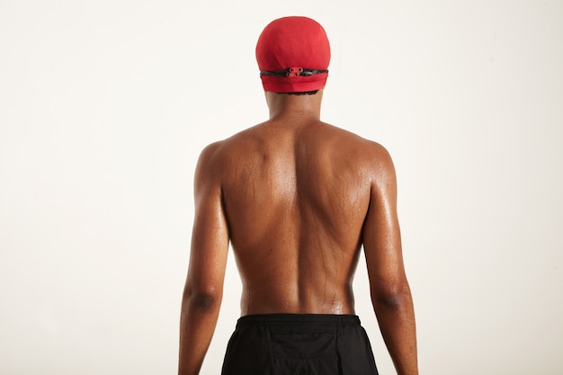wet back and head of a young muscular African American swimmer in red cap