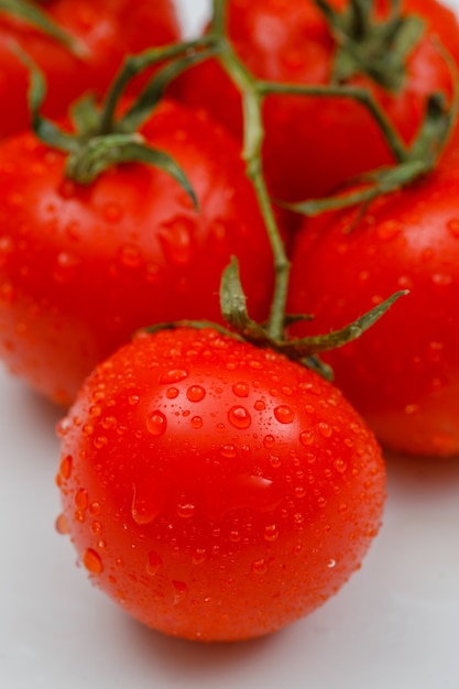Влажные спелые помидоры крупным планом на белой поверхности