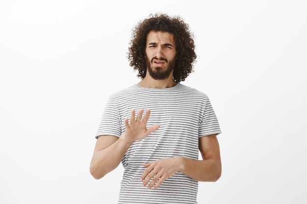 What and awful idea, no. Portrait of displeased disgusted handsome male model with beard and afro hairstyle, shaking palm in stop or enough gesture, frowning from dislike