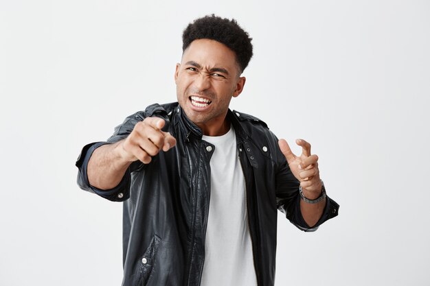 What did you say. Close up of young dark-skinned beautiful angry man with curly hair in casual clothes expressive gesticulating with hands, going to fight man who offended him.