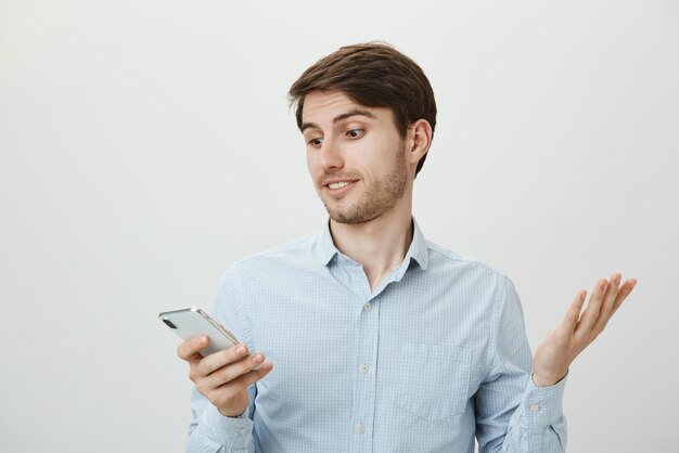 What the hell does it mean. Questioned and clueless positive handsome guy in blue shirt shrugging