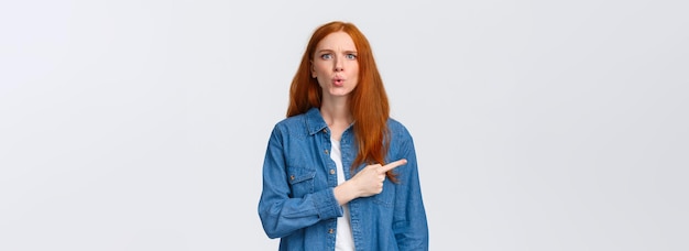 Free photo what is that alluring redhead girl in denim shirt staring questioned asking question and pointing fi