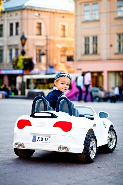 Foto gratuita come va? il ragazzo affascinante guida il piccolo cabrio bianco della bmw