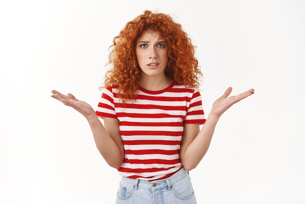 What wrong you Redhead curlyhaired young freak out complaining woman arguing shrugging dismay raise hands sideways puzzled questioned cringing bothered standing white background Copy space