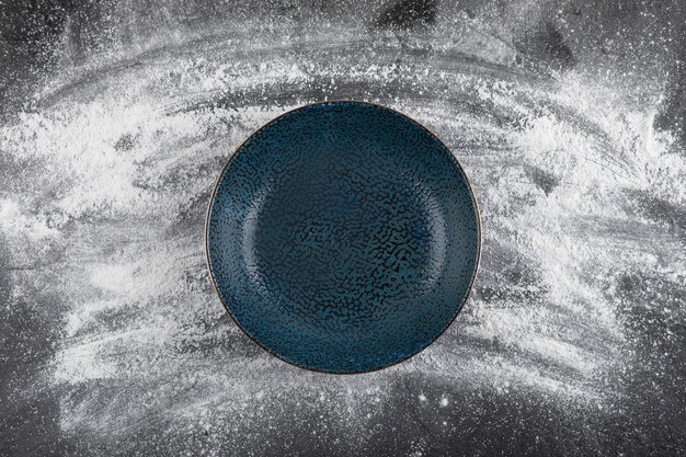 Wheat floor spilled on black surface and empty black bowl
