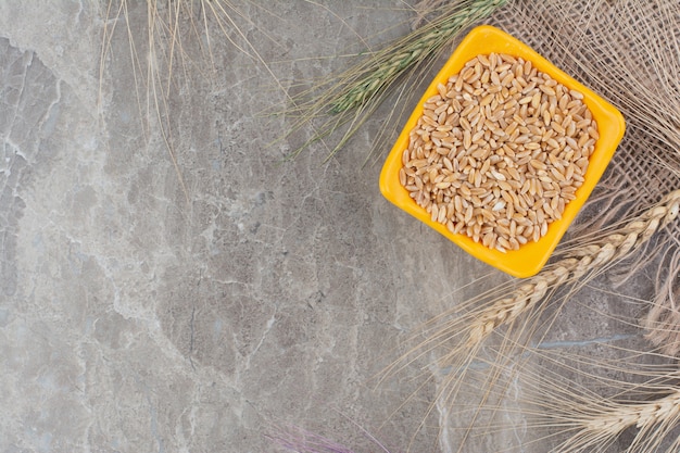 Free photo wheat grains in an orange color ceramic cup.