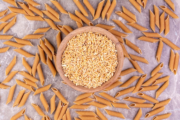 Wheat grains with pastas around on a marble surface