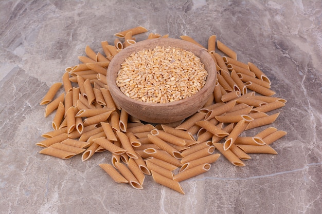 Wheat grains in a wooden cup with pastas around