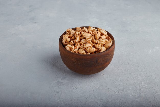 Wheat popcorns in a wooden bowl on stone background in the center. 