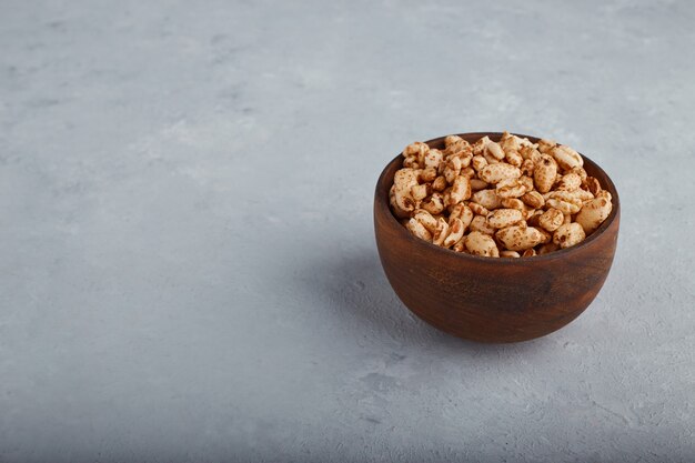 Wheat popcorns in a wooden bowl on stone background. 