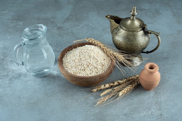 Зерна пшеницы или риса в деревянной чашке на синем фоне. Фото высокого качества